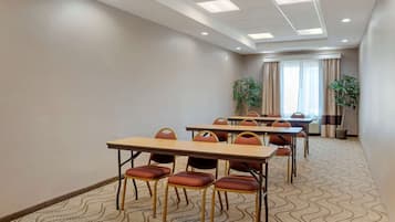 A conference room with tables and chairs, a patterned carpet, and a ceiling with recessed lighting.