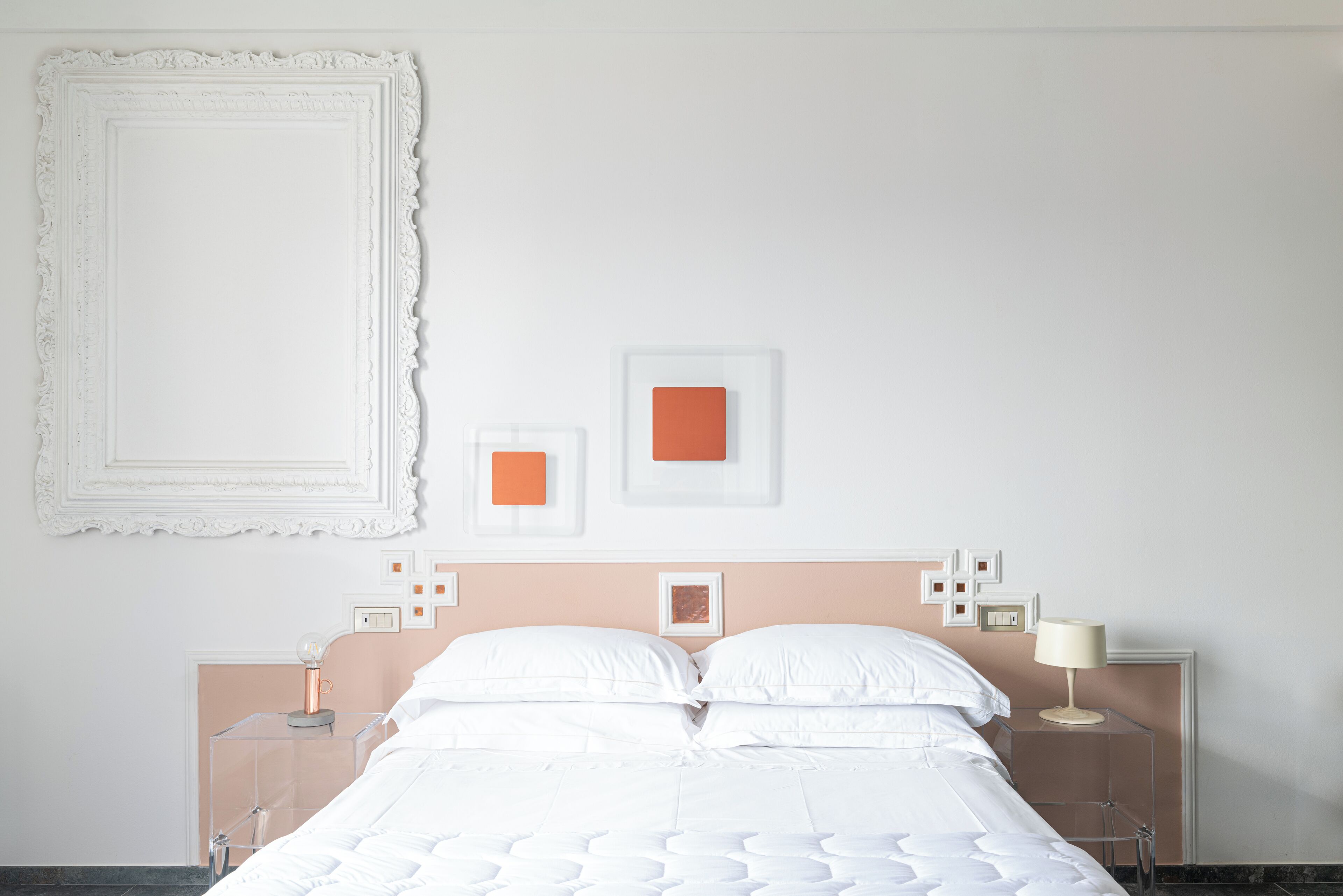 Une chambre à coucher avec un lit, des tables de chevet et des œuvres d’art accrochées au mur.