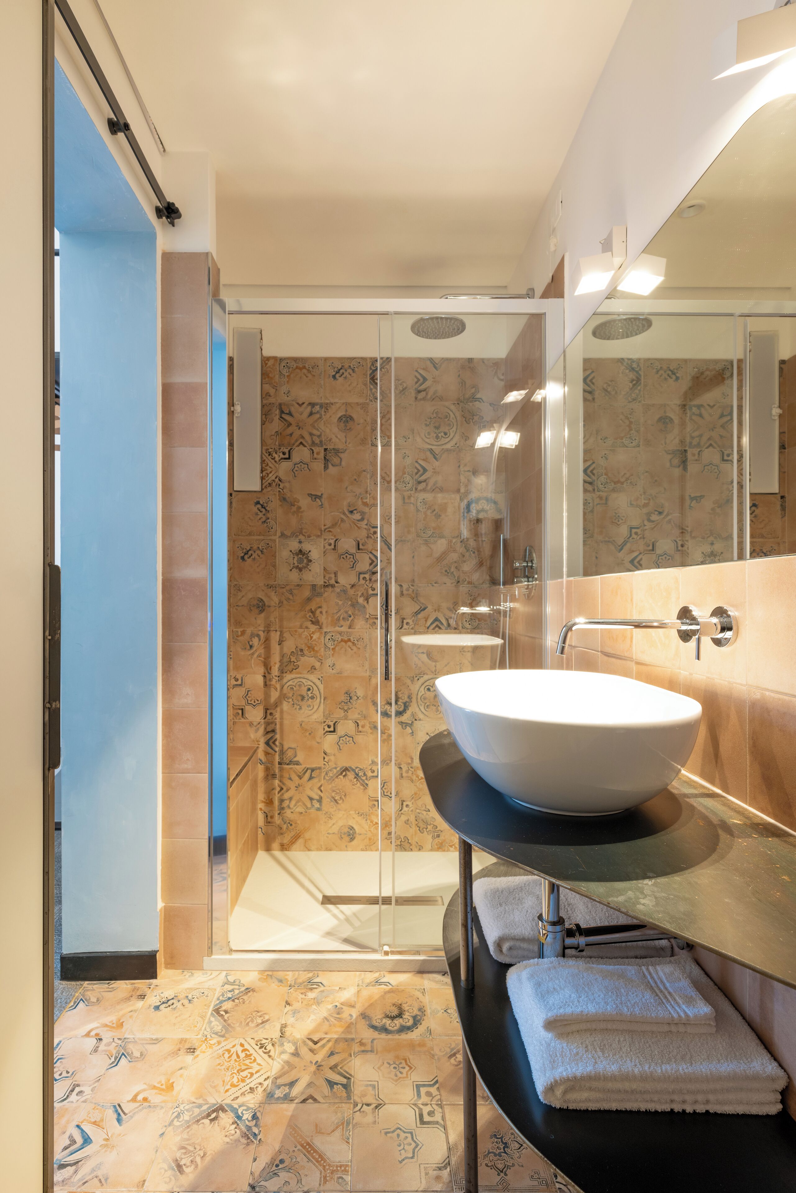 Un bagno con box doccia in vetro, un lavandino bianco e uno specchio grande.