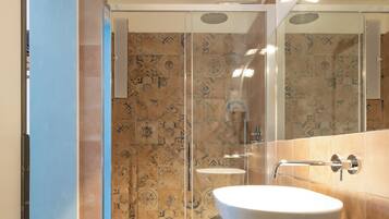 Un bagno con box doccia in vetro, un lavandino bianco e uno specchio grande.