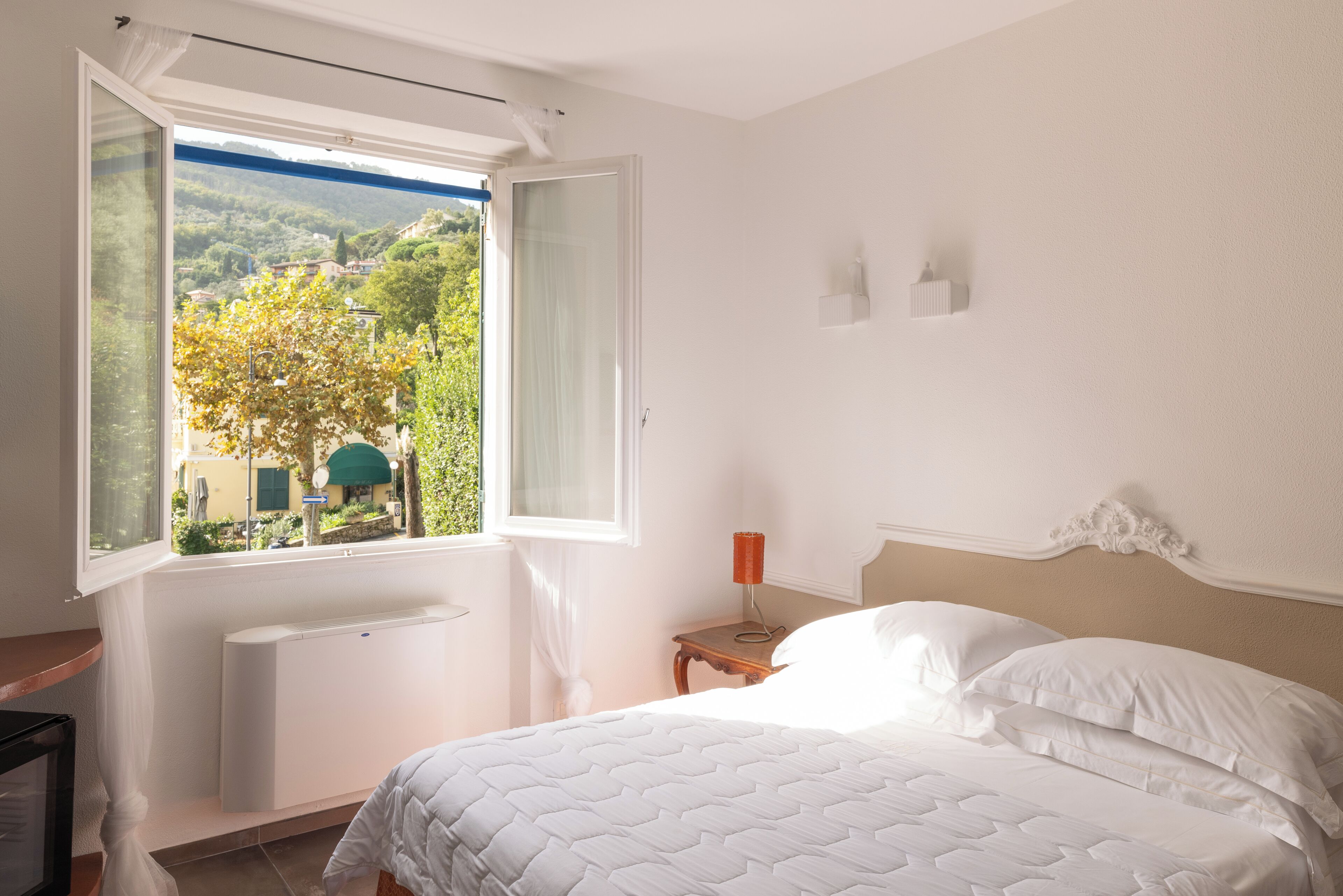 Une chambre à coucher avec un lit, une fenêtre, une table de chevet et un radiateur.