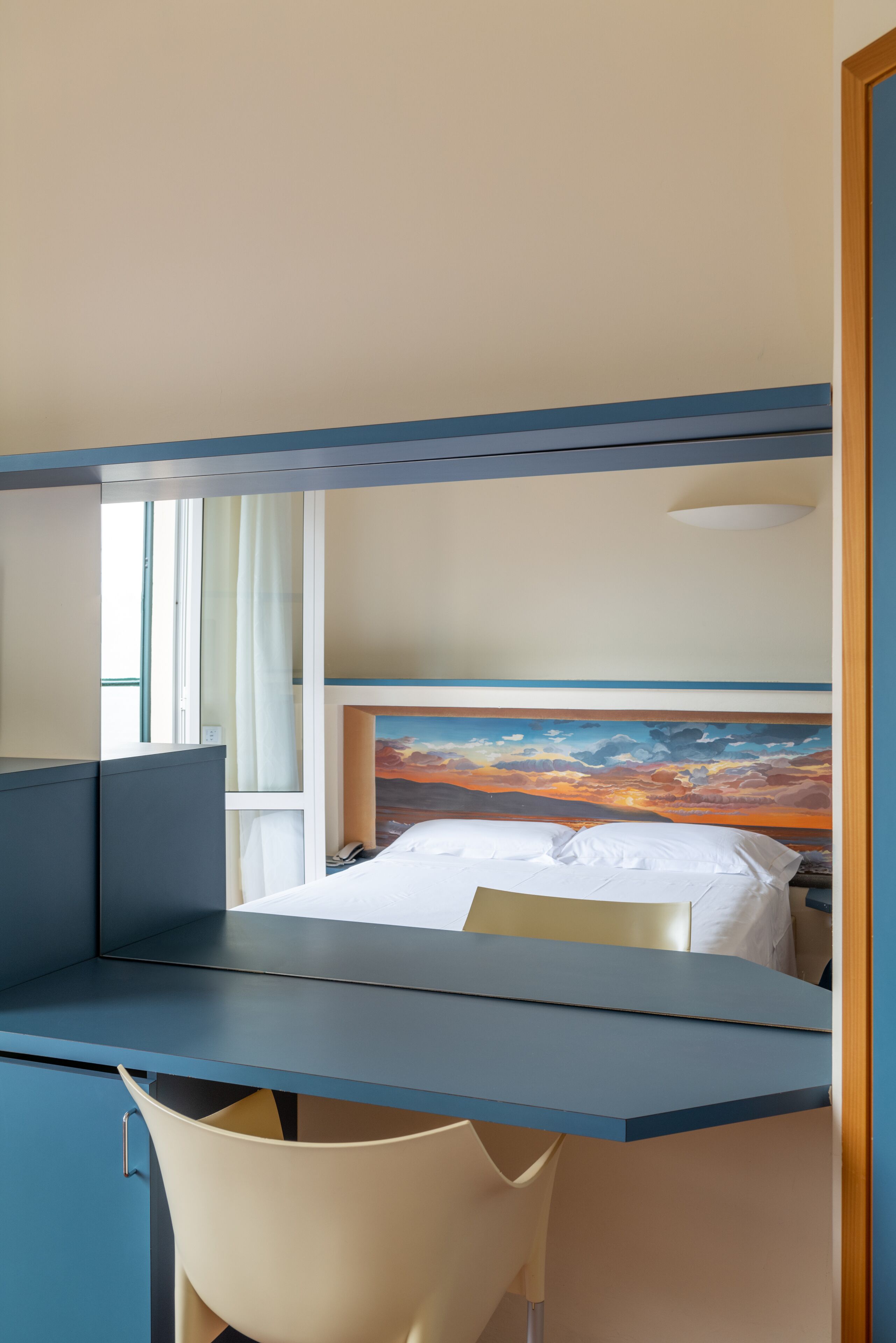 Una camera d'albergo con un letto, una scrivania e una sedia.