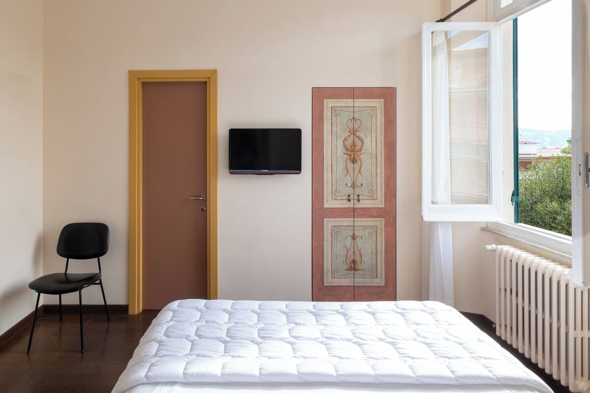 A bedroom with a bed, a chair, a television, and a door with a decorative panel.
