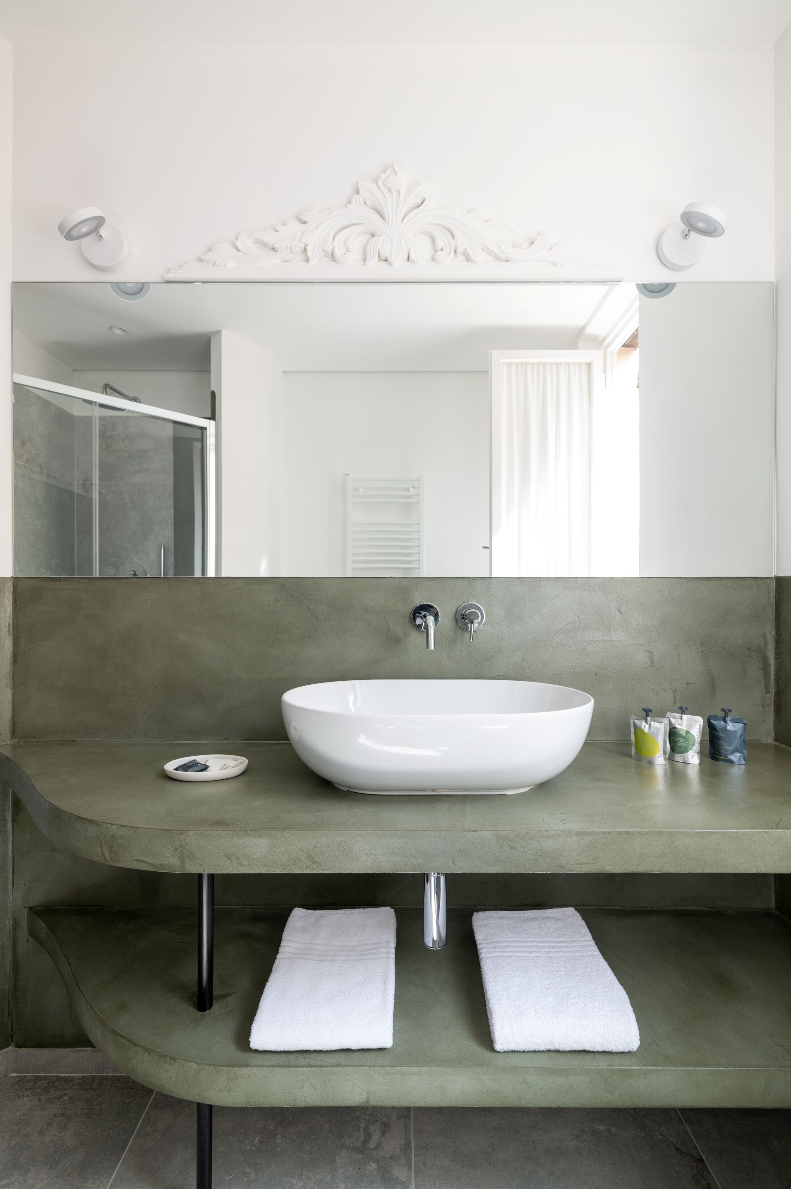 A modern bathroom with a large white sink, a mirror with decorative molding, and a towel rack with two towels.