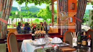 A restaurant with a table set for a meal, a view of a lake, and a mountain in the background.
