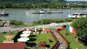 A riverside hotel with outdoor seating and a flag.