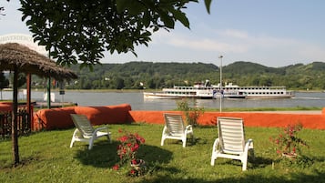 A riverside view with a boat, chairs, and a thatched structure.