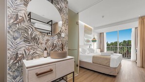 A modern hotel room with a large bed, a vanity with a mirror, and a view of the outdoors. - Valentin Grand Park Suite Hotel (Calvia)
