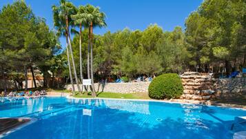 Relax by the pool surrounded by lush greenery and palm trees.