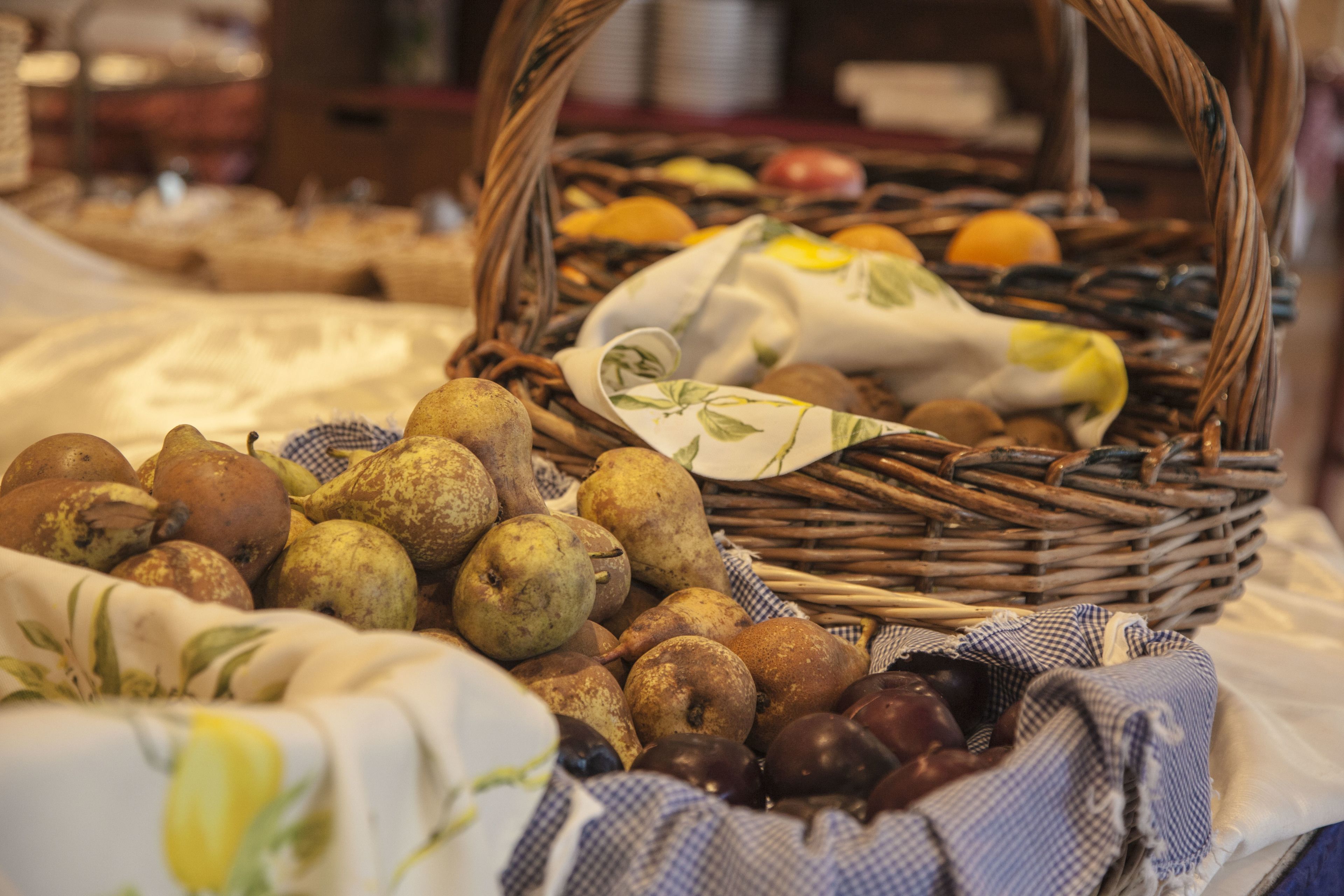 A wicker basket filled with various fruits and vegetables, placed on a table covered with a white cloth.