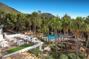 A resort with a swimming pool, outdoor seating, and palm trees.