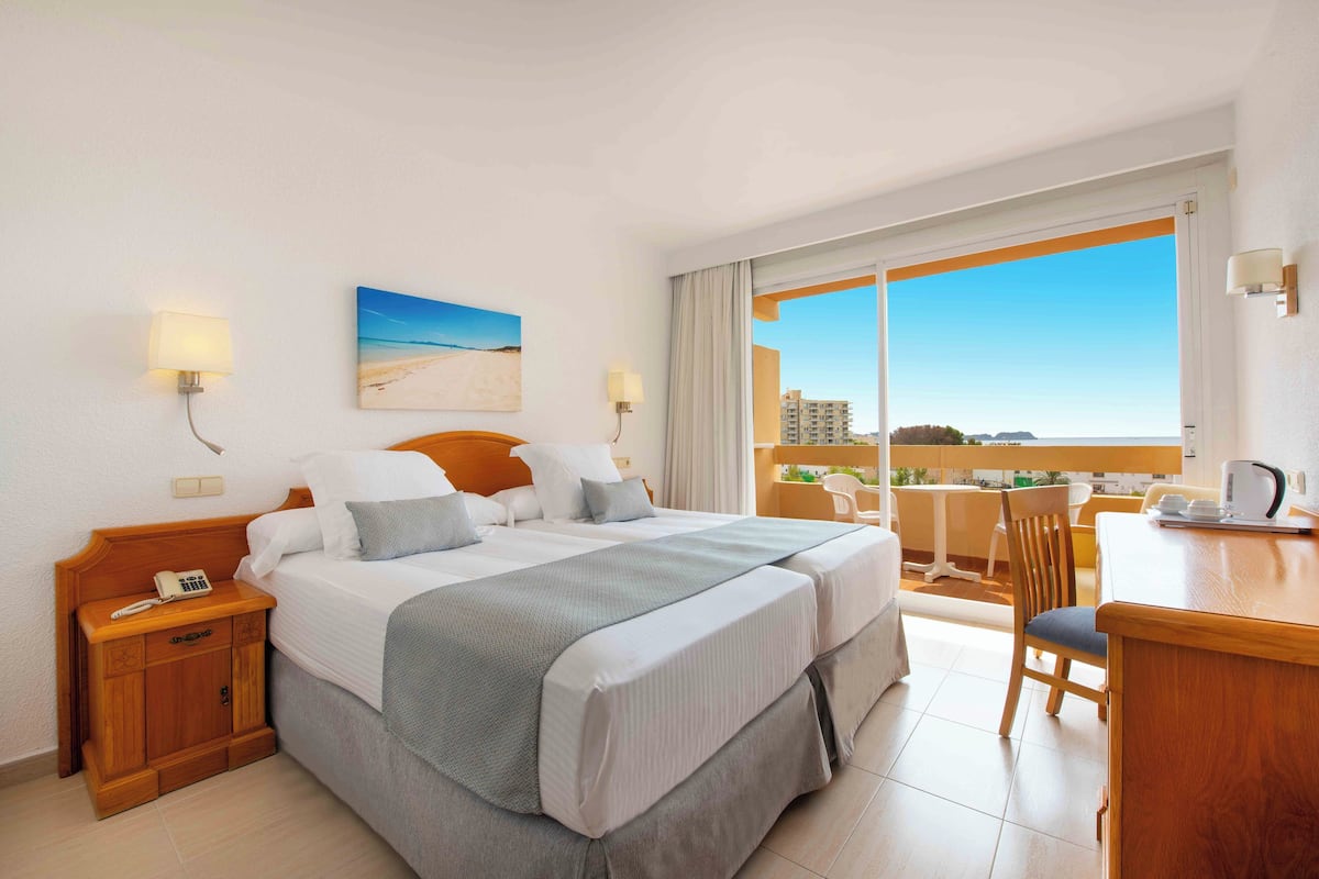 Ein Hotelzimmer mit einem großen Bett, einem Schreibtisch und Blick auf die Stadt.