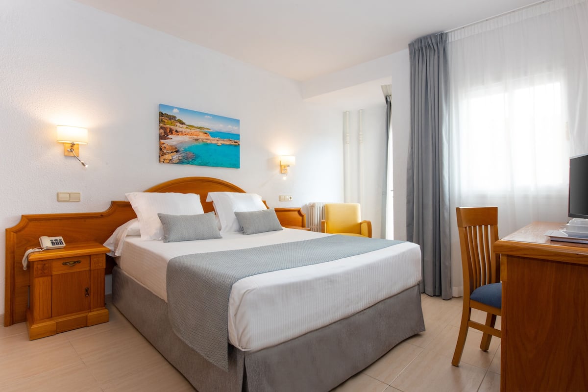 Ein Hotelzimmer mit Bett, Nachttischen, Schreibtisch und Stuhl.