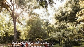 An outdoor gathering of people seated on chairs arranged in rows, with trees and greenery in the background. - Cortijo el Esparragal (Gerena)