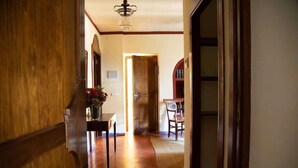 A hallway with a wooden door, a dining area with a table and chairs, and a bookshelf. - Cortijo el Esparragal (Gerena)