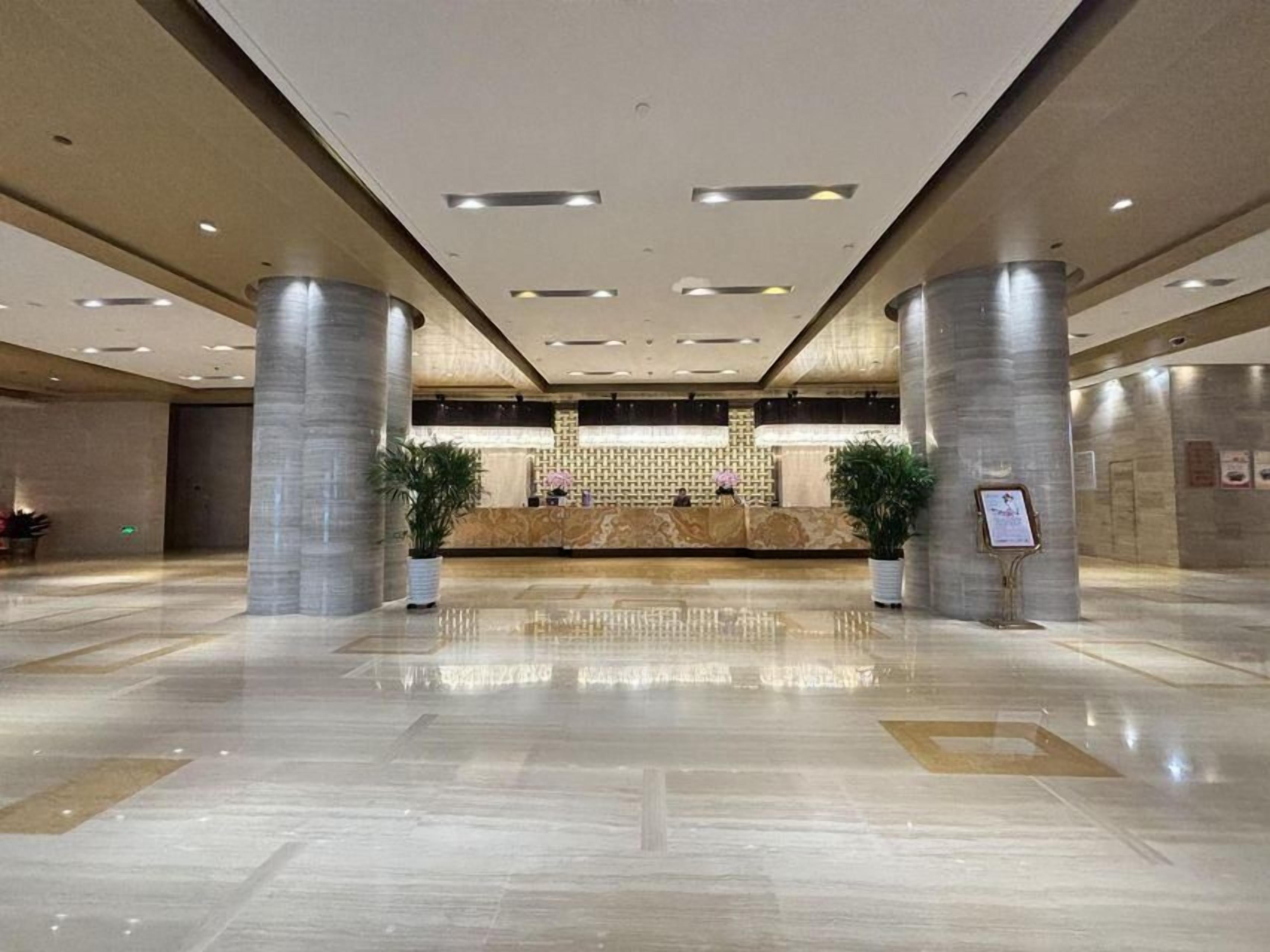A spacious lobby with a reception desk, large pillars, and a polished floor.