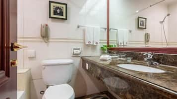 A bathroom with a toilet, sink, and mirror.
