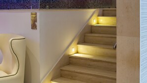 A staircase with a handrail and a chair to the left. - Golf Royal Hotel (Tunis)