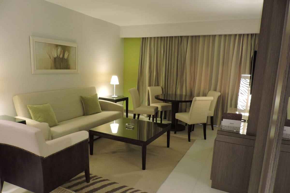 Ein stilvolles Wohnzimmer mit Sofa, Ohrensessel, Couchtisch und Esstisch.
