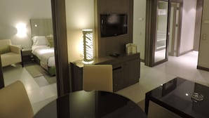 A hotel room with a bed, a desk, a TV, a lamp, and a dining table. - Golf Royal Hotel (Tunis)