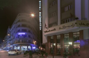 A hotel with a prominent sign, multiple floors, and a well-lit entrance.