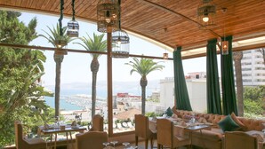 A restaurant with a view of the sea, wooden ceiling, and green curtains. - Hotel Rembrandt (Tangier)