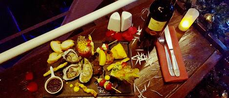A wooden table with a variety of food items, including oysters, bread, and a bottle of wine.