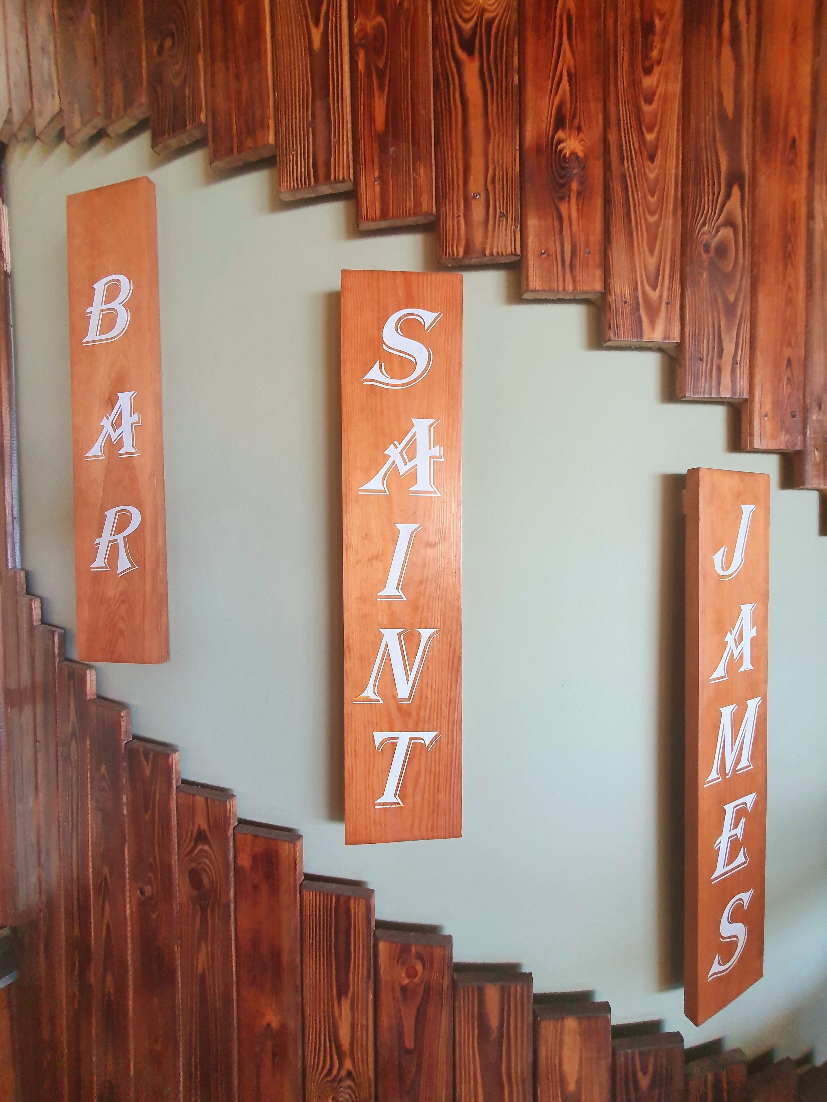 A wooden staircase with signs reading "BAR," "SAINT," and "JAMES."