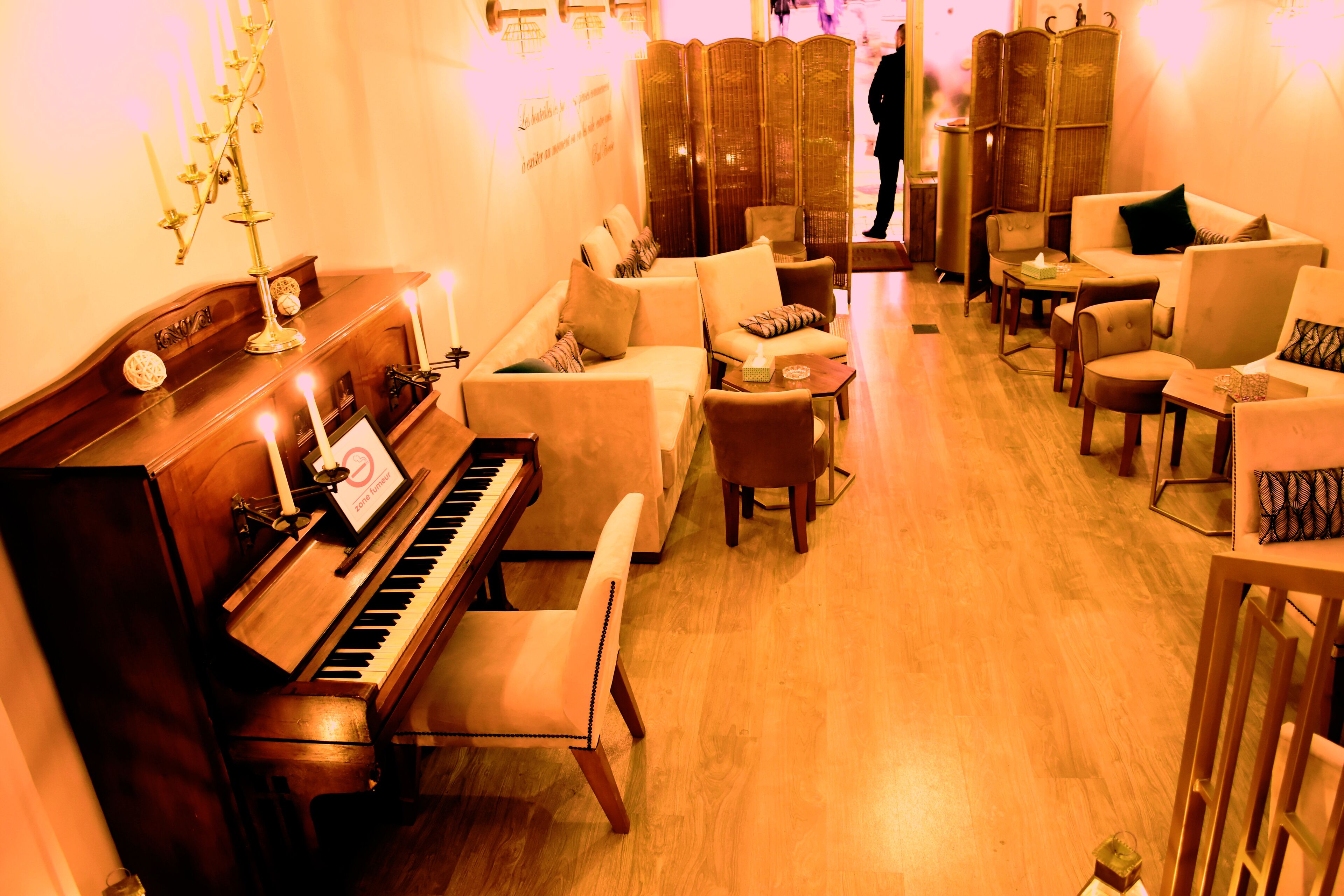 A warmly lit lounge area with a grand piano, multiple seating options, and a decorative candelabra.