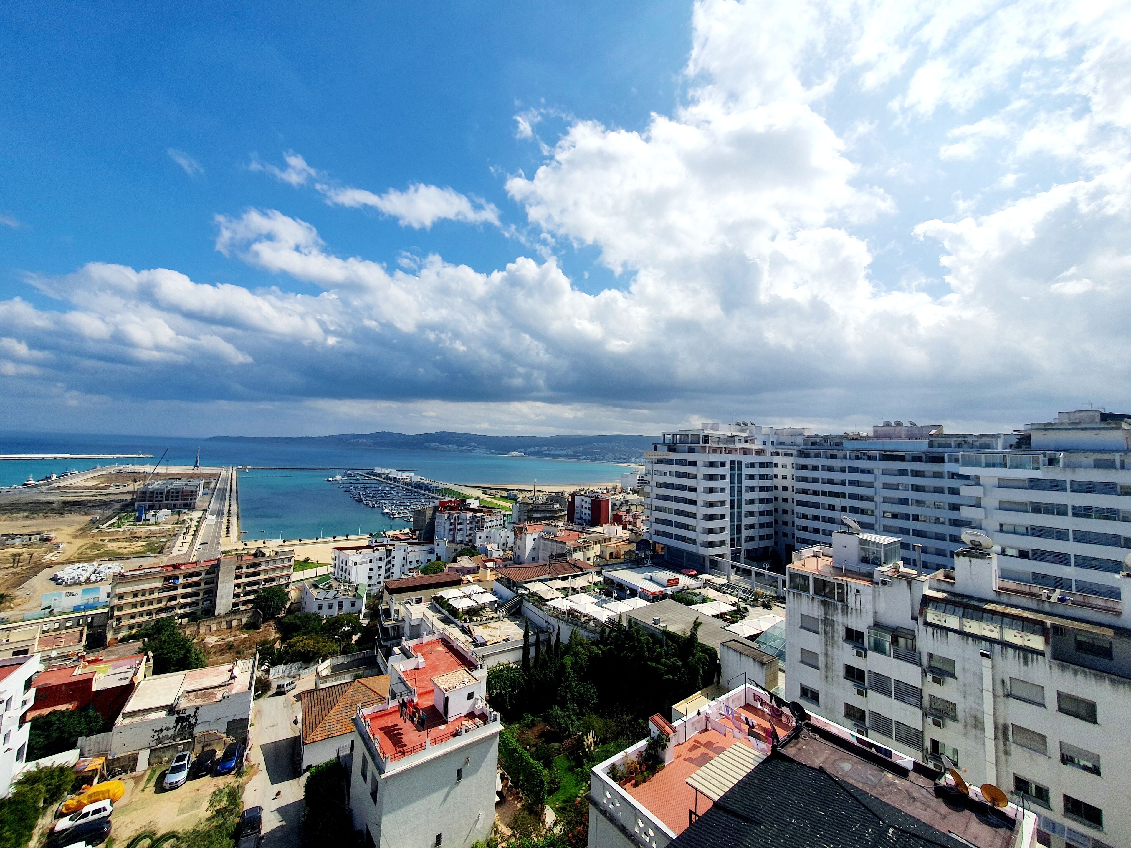 Un paysage urbain côtier avec de hauts immeubles, une marina et une plage.