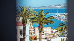A coastal marina with boats docked, palm trees, and buildings with balconies. - Hotel Rembrandt (Tangier)