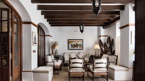 A spacious living room with a high ceiling, wooden beams, a sofa set, and a coffee table. - Hotel La Malvasía by Kaizen Hoteles (Almonte)