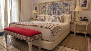 Une chambre à coucher comprenant un lit, un banc, une table de chevet et un mur orné d’un motif décoratif en carreaux.