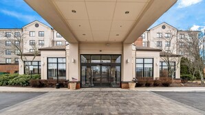 A modern building entrance with a covered walkway, large windows, and a welcoming sign. - Hilton Garden Inn Plymouth (Plymouth)