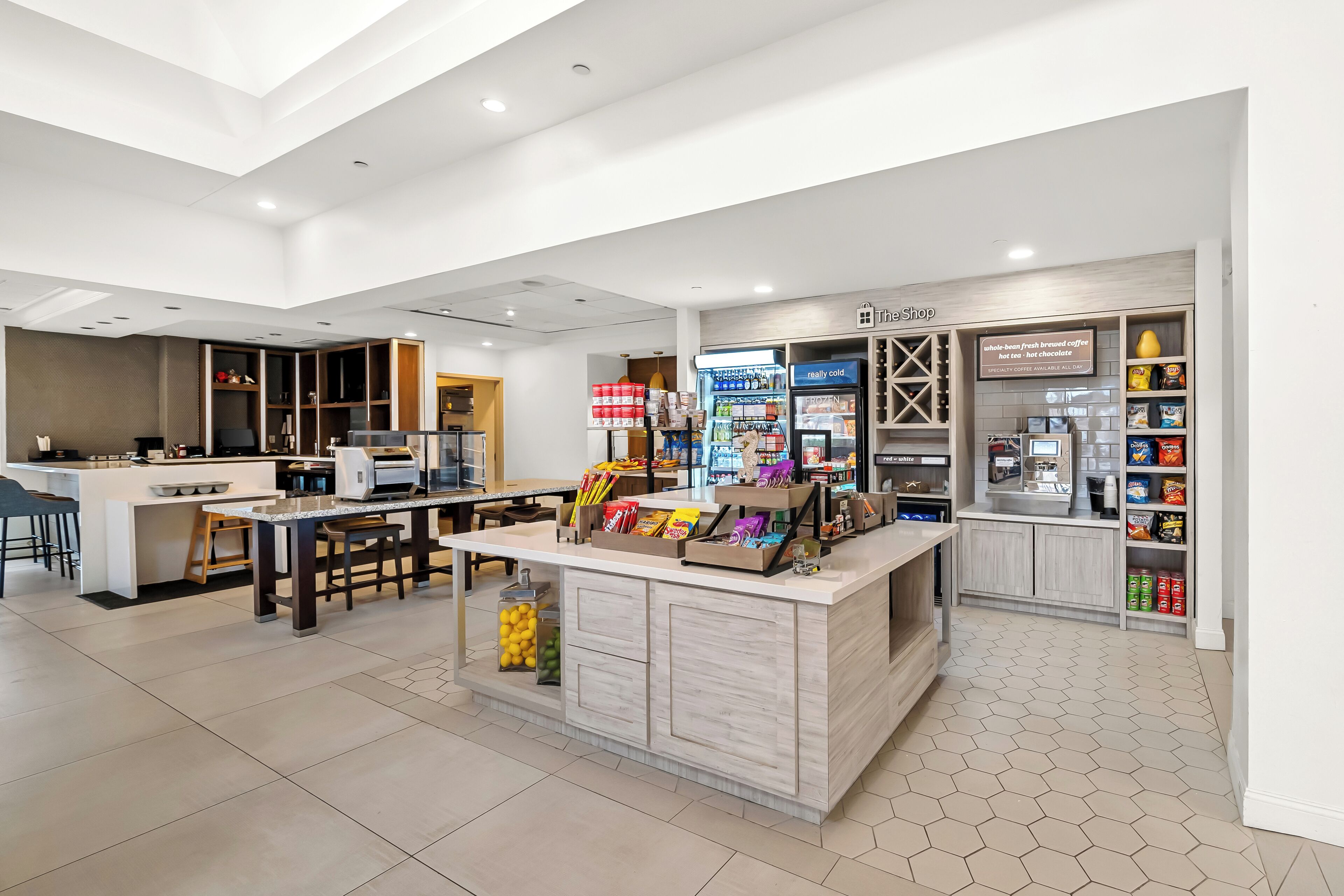Un área de cocina moderna con una isla central, taburetes de bar y un espacio para sentarse.