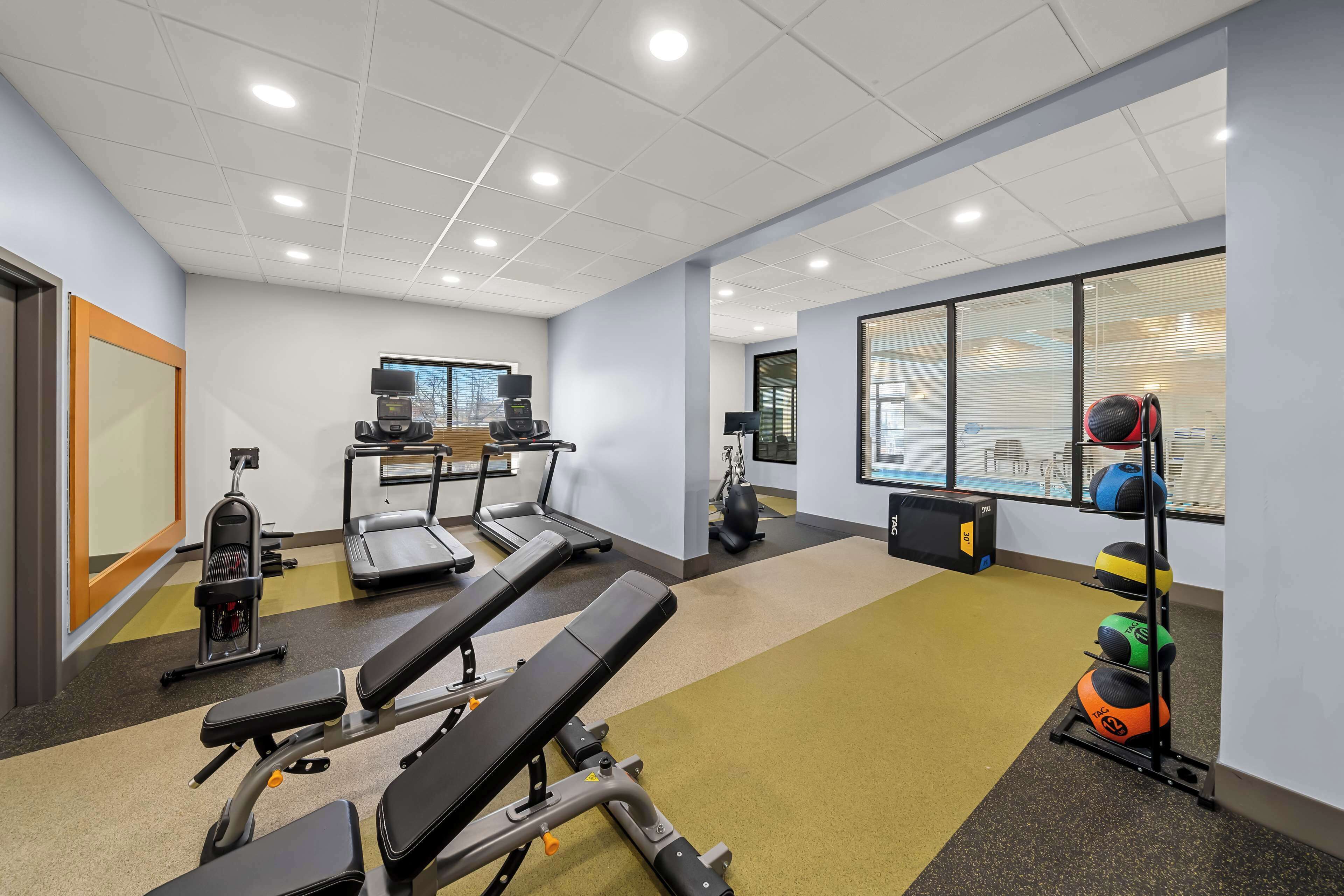 Une salle de sport équipée de matériel d’exercice, notamment des tapis de course, un vélo d’appartement et des appareils de musculation.