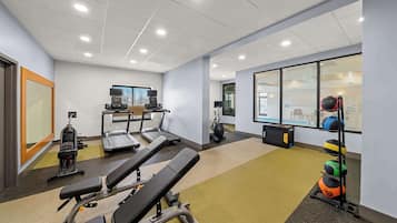 Une salle de sport équipée de matériel d’exercice, notamment des tapis de course, un vélo d’appartement et des appareils de musculation.