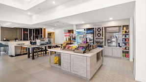 A modern kitchen area with a central island, bar stools, and a refrigerator stocked with beverages. - Hilton Garden Inn Plymouth (Plymouth)