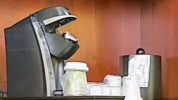 A coffee machine with a drip tray, a milk frother, and a coffee grinder on a countertop.