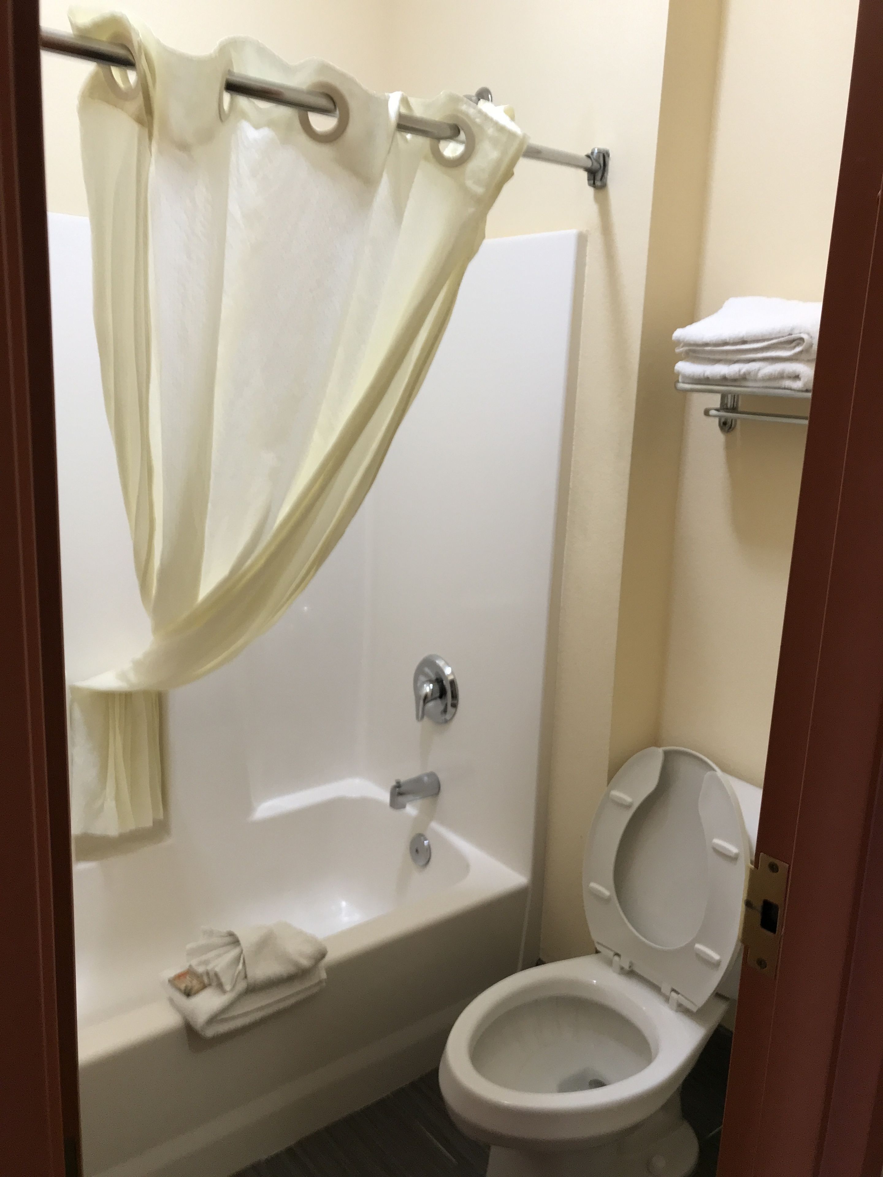 A bathroom with a bathtub, toilet, and a towel rack.