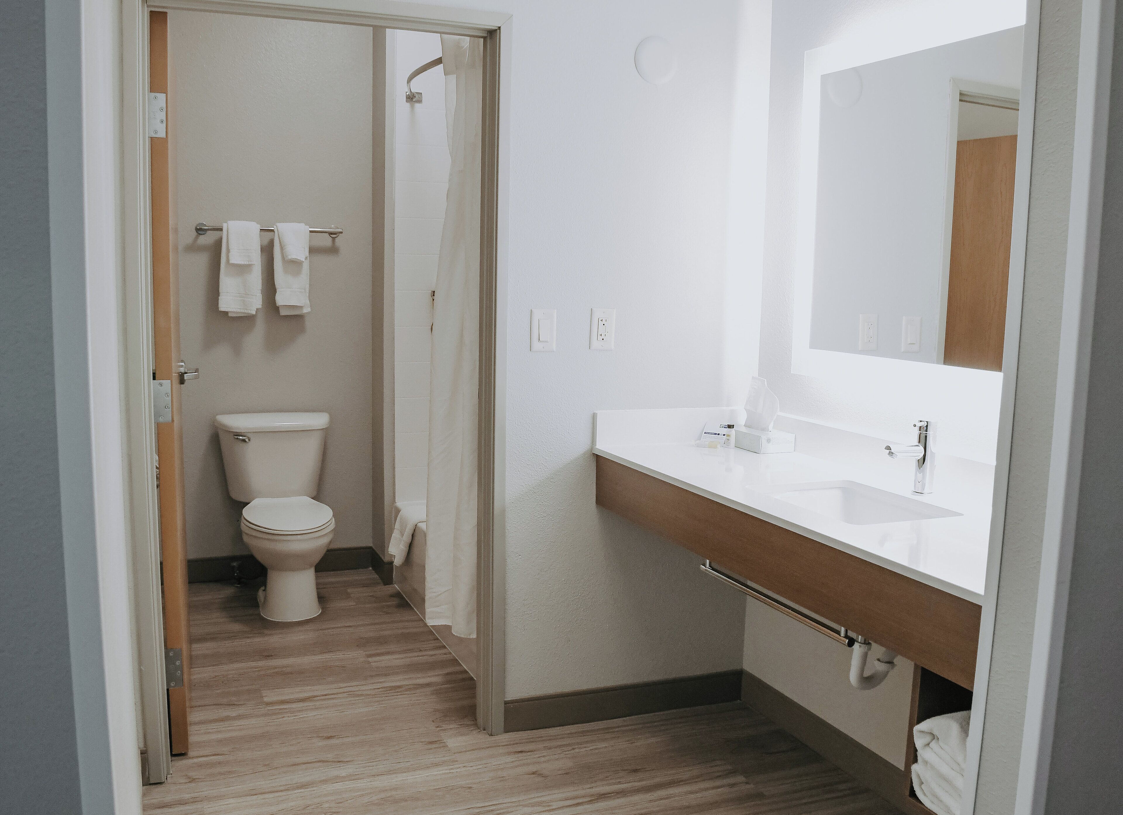 Un baño con inodoro, ducha y lavamanos con espejo.