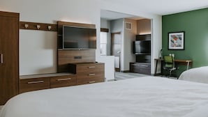 A hotel room with a large bed, a wooden dresser, a flat-screen TV, a desk with a chair, and a green accent wall. - Holiday Inn Express & Suites South - Lincoln by IHG (Lincoln)