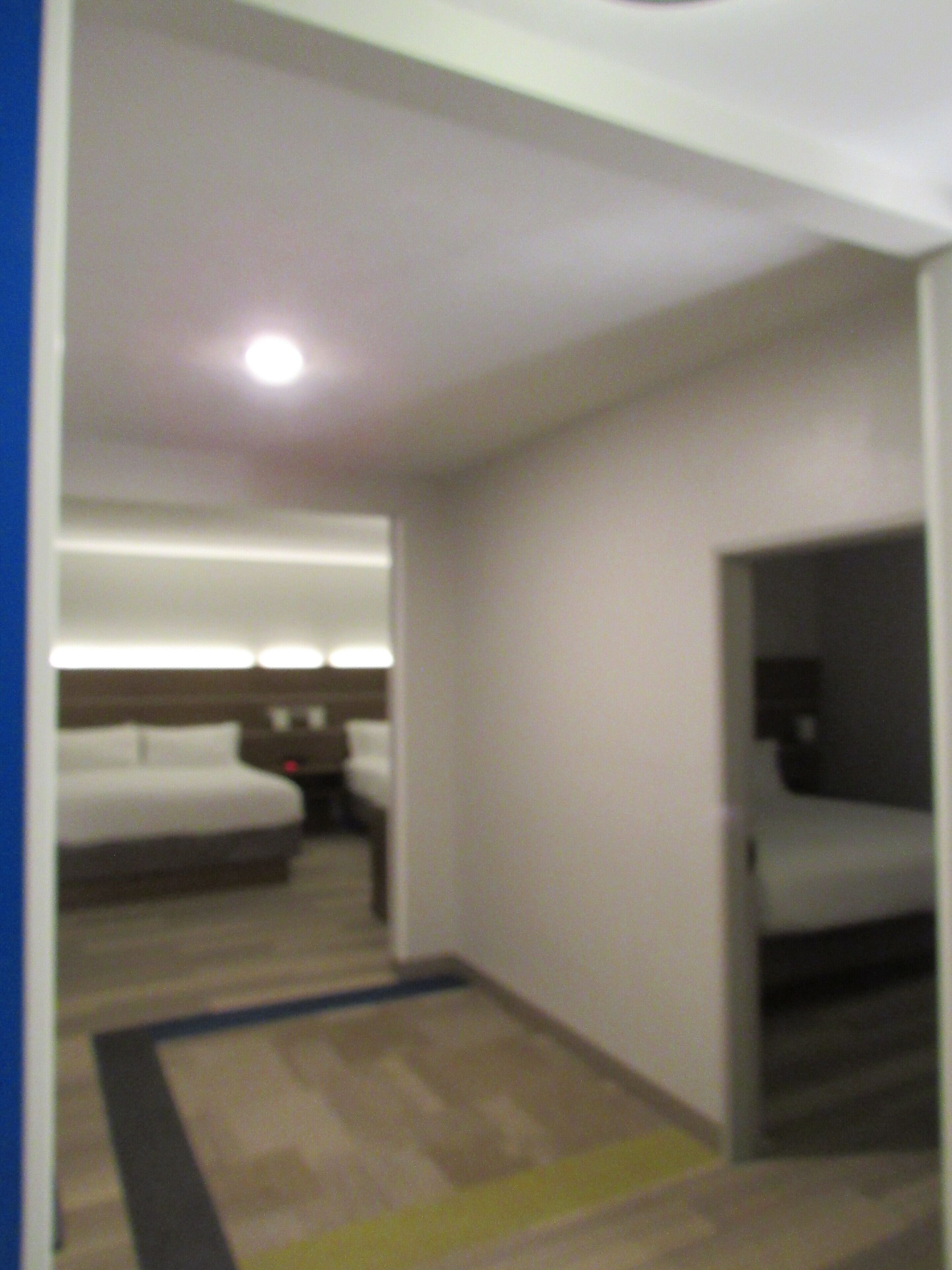 Habitación de hotel con cama, mesita de noche y un pequeño escritorio.
