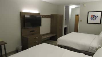Une chambre d’hôtel avec deux lits, une télévision, une armoire et un tableau encadré au mur.