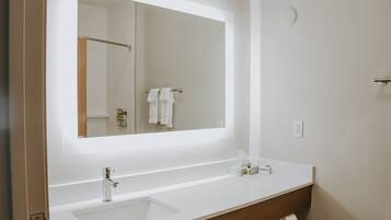 A bathroom with a white sink, a mirror, and a toilet.