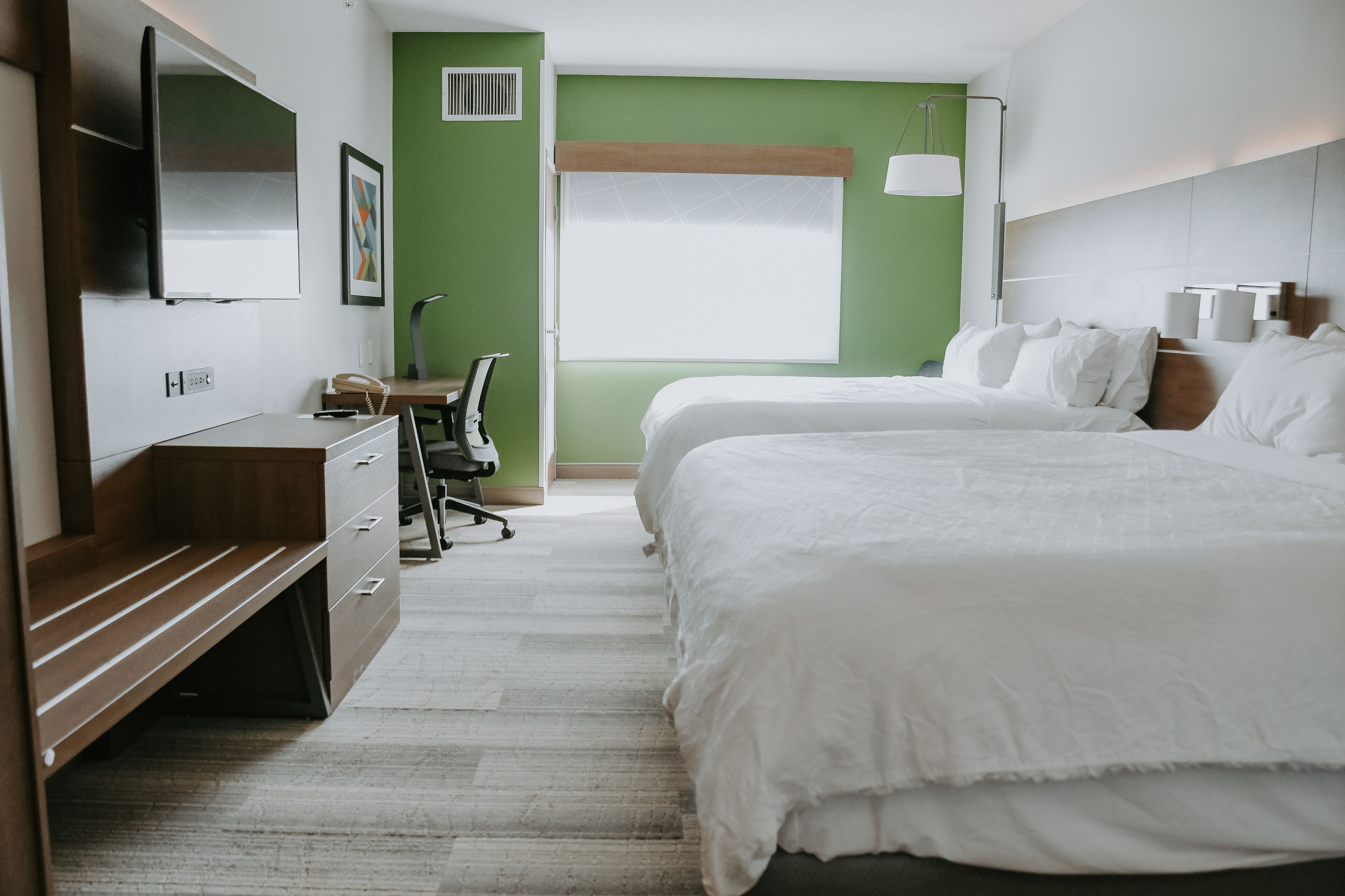 Una habitación de hotel con una cama, un escritorio, una silla, un televisor y una ventana.