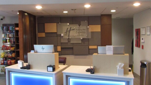 A hotel reception area with two reception desks, a Holiday Inn Express sign, and a small kiosk with snacks. - Holiday Inn Express & Suites South - Lincoln by IHG (Lincoln)