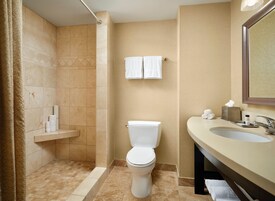 A bathroom with a shower, toilet, sink, and towel rack.