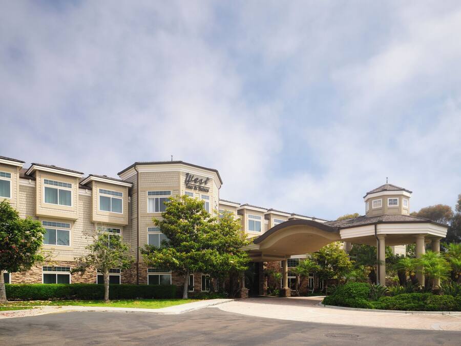 A hotel with a modern architectural design, featuring a prominent entrance with a covered walkway and a small tower-like structure.