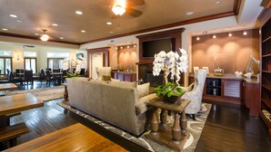 A spacious living area with a sofa, dining tables, and a fireplace. - West Inn & Suites (Carlsbad)
